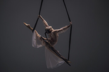 Girl aerial gymnast demonstrates stretching in twine on acrobatic trapeze. Acrobatic athlete...