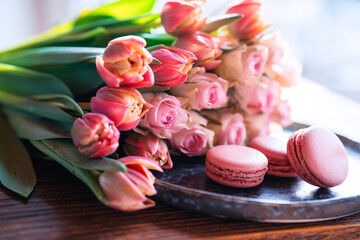 Beautiful pink bouquet of flowers and fine delicacies on dark wood. Sweet pastries with roses and...