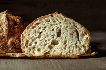 Bread, traditional sourdough bread cut into slices on a rustic wooden background. Concept of traditional leavened bread baking methods. Healthy food.