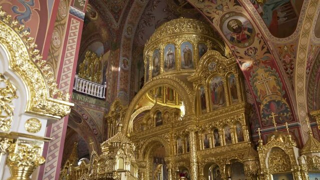 Lavish golden interior of an Orthodox cathedral with intricate iconography and frescoes, reflecting religious art and architecture.