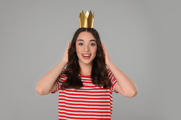 Beautiful young woman with princess crown on grey background