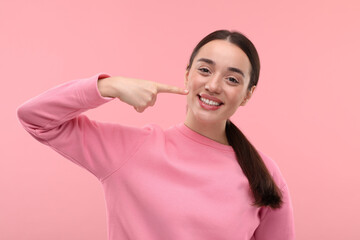 Beautiful woman showing her clean teeth and smiling on pink background
