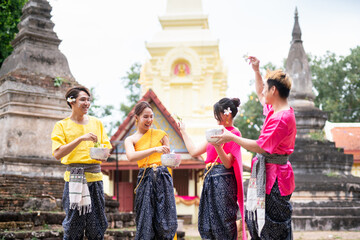 Group of Asian people wearing thai dress traditional pose happiness to playing splash water during...