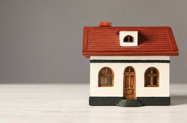 Obraz na płótnie Canvas Mortgage concept. House model on white wooden table against grey background, space for text