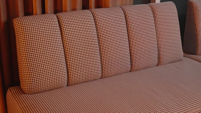 Stylish houndstooth chair elegantly adorned with a luxurious orange satin sheet, emphasizing contrast in textures and colors. Ideal for interior design themes or home decor showcases.