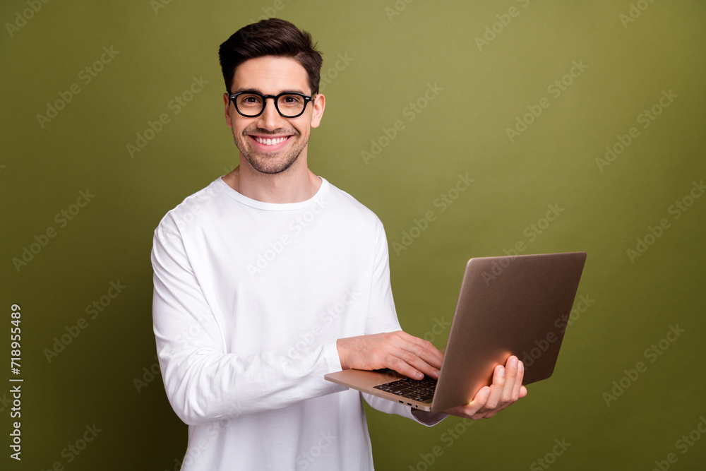 Sticker Photo of young optimistic system administrator man in white pullover typing keyboard his netbook isolated on khaki color background