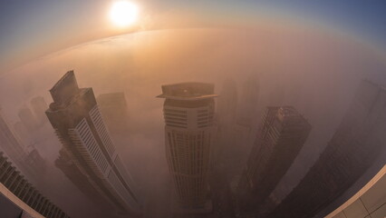 Rare early morning winter fog above the Dubai Marina skyline and skyscrapers lighted by street...