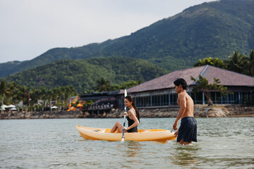 Fototapeta na wymiar Active Asian Couple Enjoying Kayaking Adventure on a Tropical Lake
