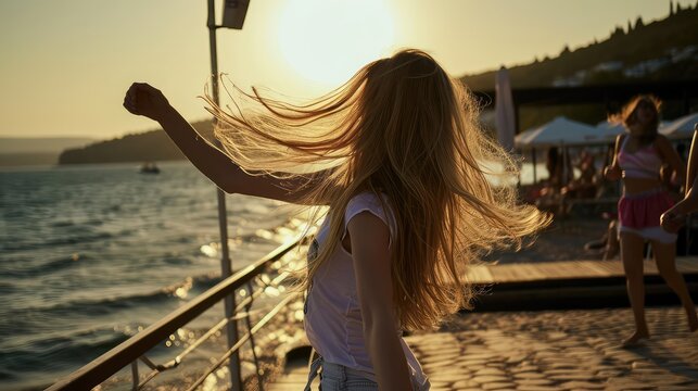 A girl dances in the rays of the setting sun in a beach cafe