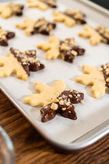 Obraz na płótnie Canvas Making Cutout Sugar Cookies, Chocolate-Dipped, Hazelnut-Sprinkled