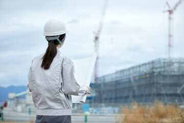 建設現場と作業服を着た女性