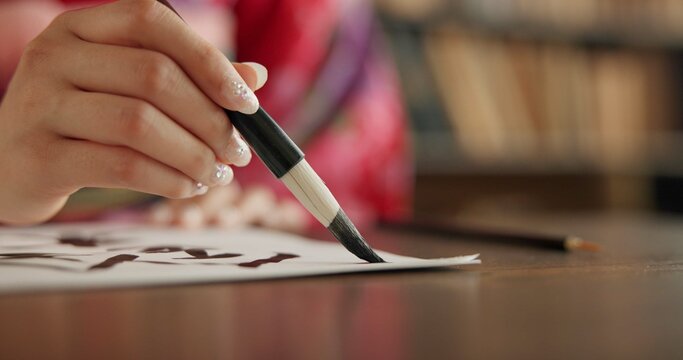 Ink, Japanese writing and person in traditional home for script, documents and paper on desk. Creative, Asian culture and hands with vintage paintbrush tools for calligraphy, font and text in house