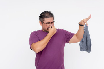 A man in a purple shirt pinches his nose and gestures with disdain at a foul-smelling gray underwear.