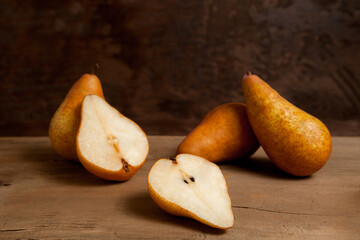 Whole and halves of pears on wooden background..