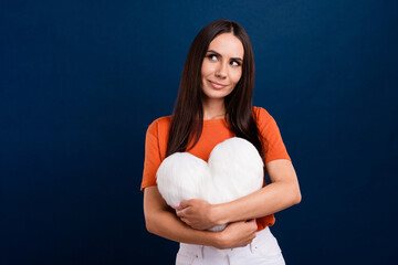 Photo of stunning dreamy lady wear orange t-shirt cuddling soft white pillow looking empty space isolated dark blue color background