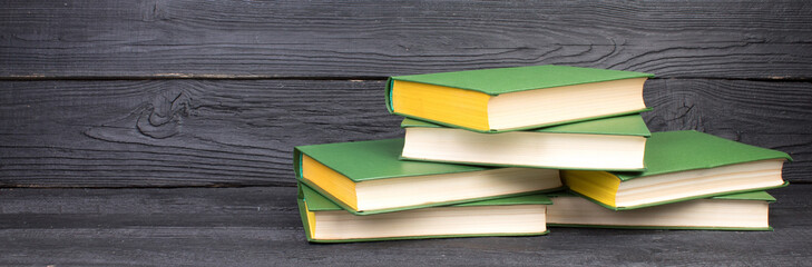 Books on wooden table, black board background. Back to school. Education business concept. panorama, banner.