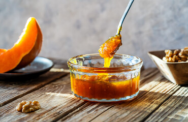 Autumn Harvest Pumpkin and walnuts Jam on wooden table, spoon with jam
