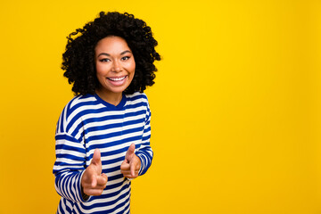 Photo of positive adorable girl wear stylish clothes looking camera fingers indicating you empty space isolated on yellow color background
