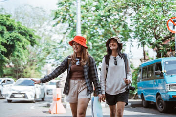 two beautiful local tourists enjoying a walking vacation carrying a camera and a map to a tourist spot