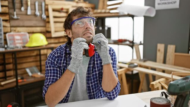 Nervous young carpenter biting nails, showcasing stress and anxiety problem at carpentry - indoor shot of worried hispanic man with beard