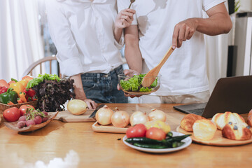 Happy love Asian young man and woman cooking food together in the kitchen relaxing at home.