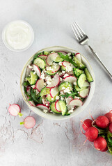 Vegetarian salad of radishes, cottage cheese, sour cream and arugula on a white background. Top view. 