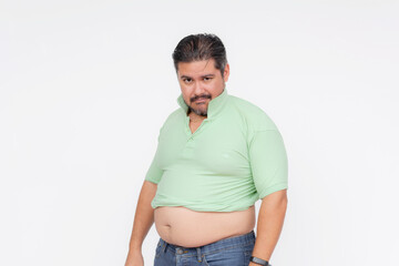 An overweight man looks annoyed after his old shirt barely fits, his belly sticking out. A...