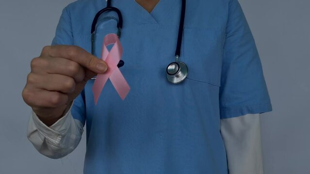 Doctor holds artificial model of female breast and pink knot. Breast cancer