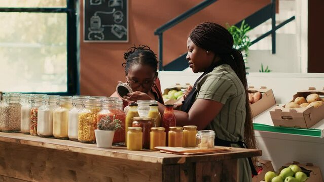 Storekeeper offering food sample for a taste test in supermarket, advertising eco friendly homemade products. Vendor providing amazing customer service, recommending various bulk items.