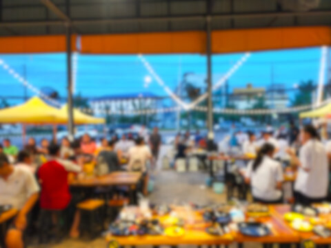 The picture blurs the atmosphere inside a Korean BBQ restaurant with many people eating and coming over.