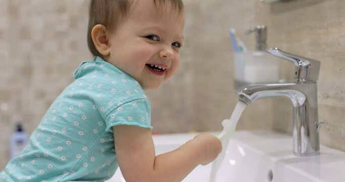 Little baby child girl brushing her teeth with toothbrush in bathroom