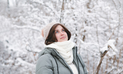 young woman looking up on winter nature, pretty beautiful girl among trees covered with snow walking in white forest and enjoying