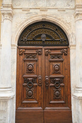 Beautiful carved wooden door across marble wall close-up. Building exterior, facade