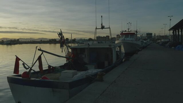 Fishing boats and ships in the port of Castellon in winter. Port cranes on the horizon. Red floats for nets. Port of El Grao. Spain