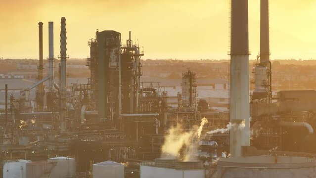 Close view of smog-filled air above fuel refinery in Cape Town, South Africa. A fire is adding smoke to the sky. Table Mountain in background. Focus on smoke stack pumping pollution into the air. 