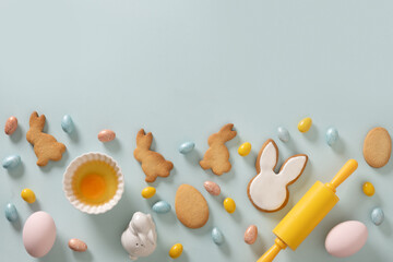 Easter frame with cookies, Easter eggs, bunnies shaped, whisk on blue background. Space for text....