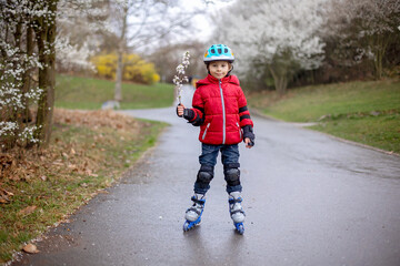 Little child, preschool boy in protective equipment and rollers blades, riding on walkway