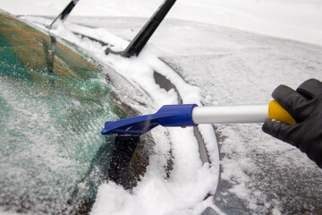in winter, the car window is cleaned of ice with a scraper