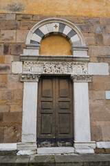 Fototapeta na wymiar Beautiful wooden door of the Church Chiesa di San Salvatore in Lucca, Tuscany, Italy