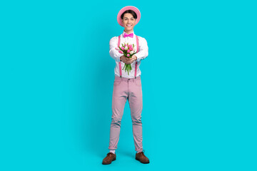 Full body photo of good mood guy wear white shirt bow tie pink headwear give you bouquet on birthday isolated on blue color background