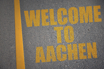 asphalt road with text welcome to Aachen near yellow line.