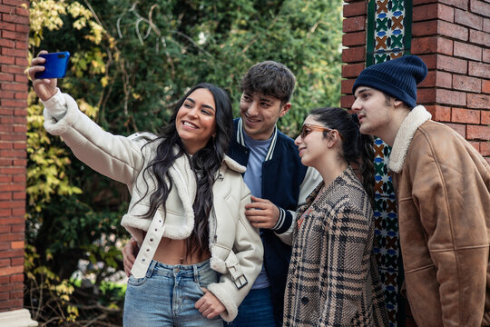group of four young friends taking selfie with the phone