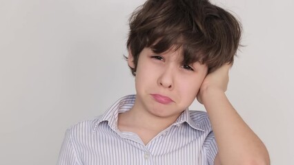 Pre-teen grimacing with one hand against his forehead, indicative of either physical or psychological discomfort. Can represent articles on childhood stress management.