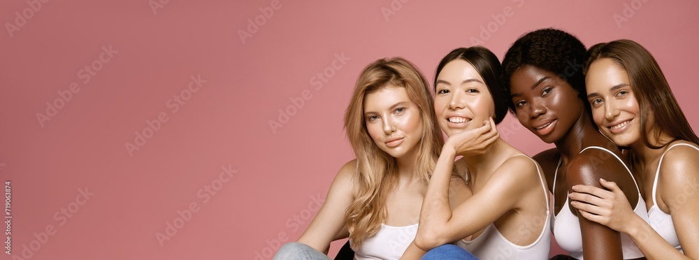 Wall mural multi ethnic group of womans with diffrent types of skin sitting together and looking on camera. div