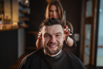 Smiling bearded Man portrait while undercut hairstyle hairdressing in Hair Salon by young...