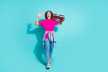 Full body photo of teenager guy wearing pink t shirt with jeans greetings to friends with boombox isolated on aquamarine color background