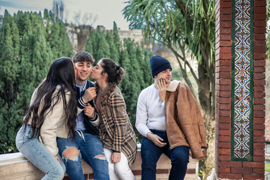 two girls kissing boy and another boy being the third wheel