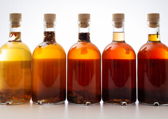 Bottles with transparent brown alcoholic drink on a white background. Homemade herbal tincture of herbal moonshine. Elite alcohol.