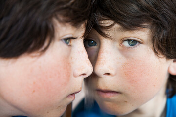 Boy looking in the mirror with autism spectrum disorder. Concept of autism in children