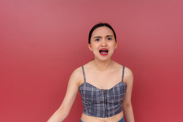A young Asian woman nagging and complaining, yelling with an annoying voice. Isolated on a red...